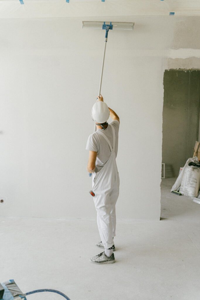 Back View of a Person Painting the Wall Using a Painting Brush Roller